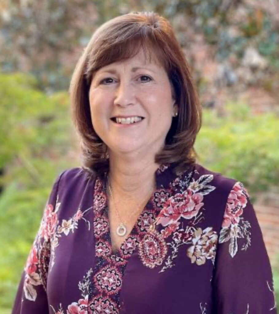 An individual posed outside and smiling at the camera.