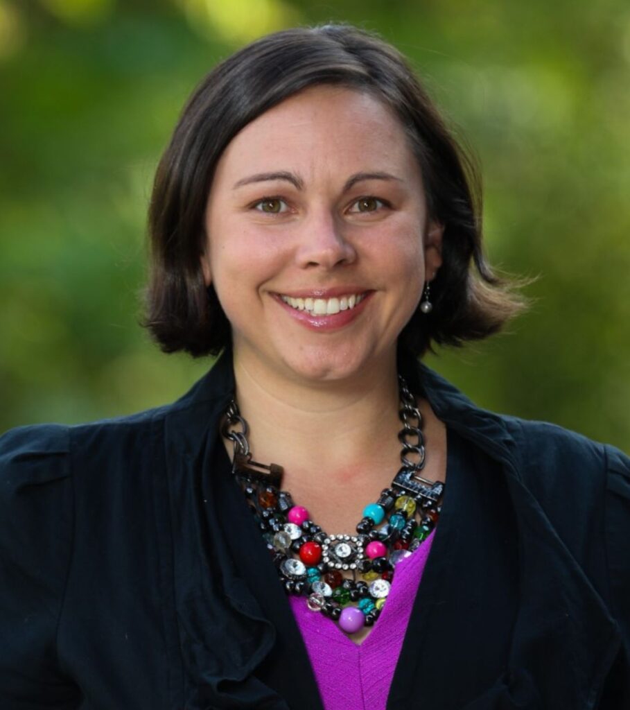 An individual in business casual dress smiling at the camera.