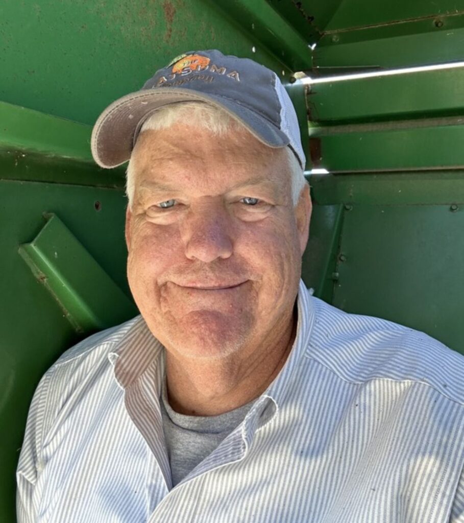 An individual in a ball cap smiling at the camera.