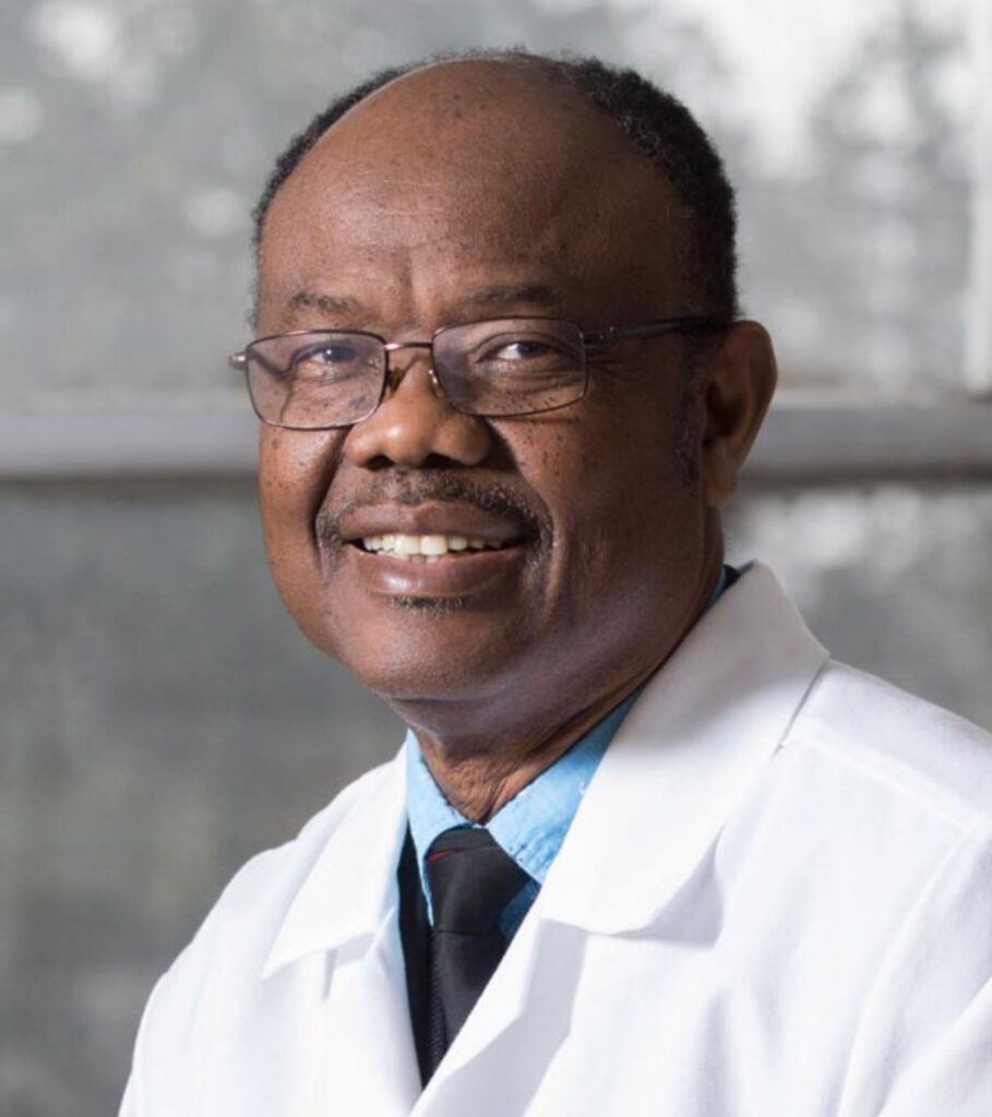 An individual in a lab coat smiling at the camera.